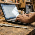 Hand mit a Computer in einer Drechsler- Werkstatt mit Sägemehl sichtbar